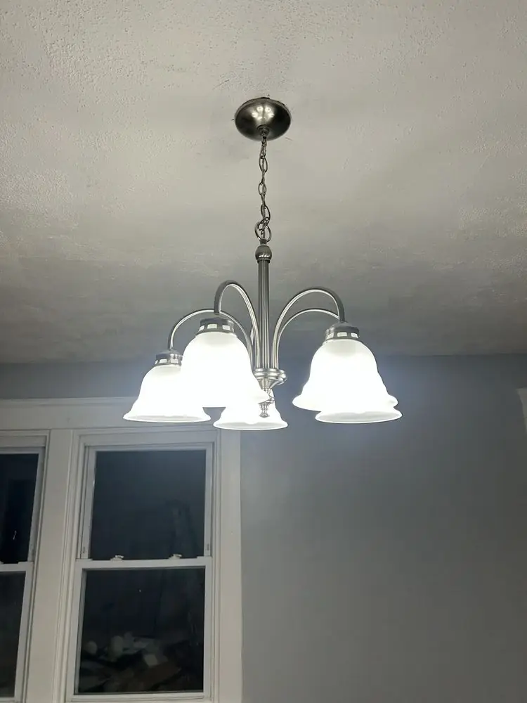 A newly hung five-light chandelier over a dining area