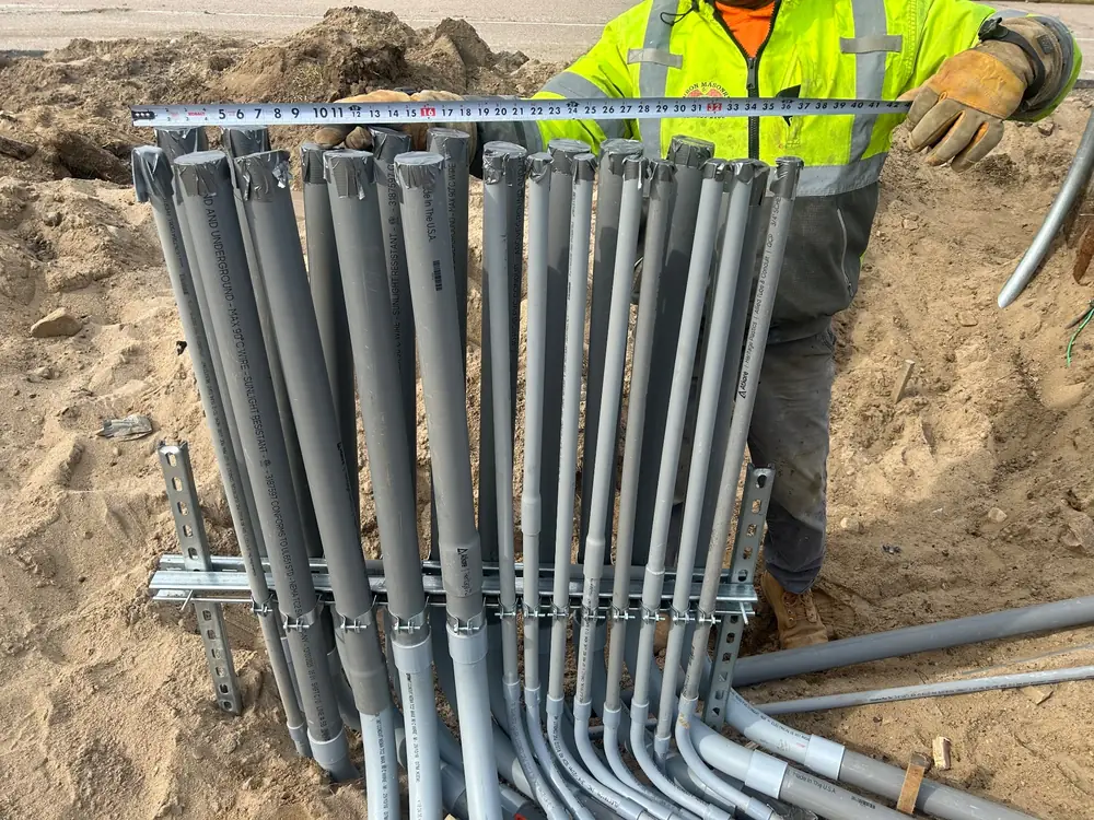 A bank of EMT conduit stubbed up out of a sand trench on a construction site