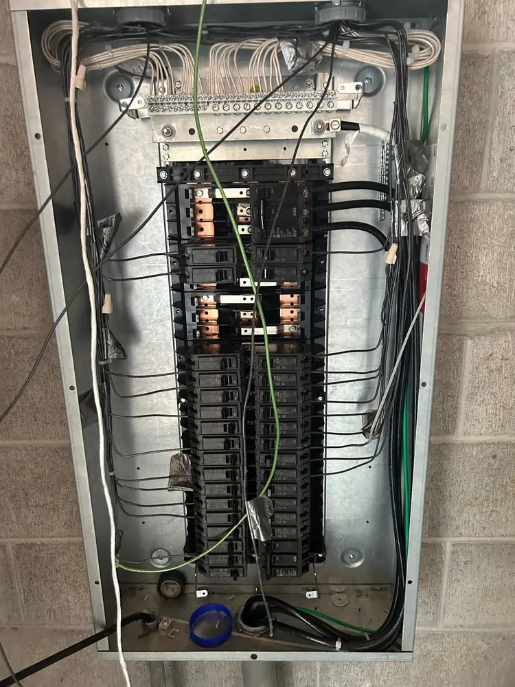 An open panel on a block wall with every conductor neatly routed to its breaker
