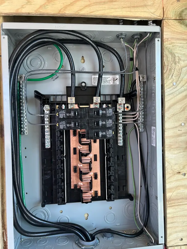 A new panel on a plywood backboard with clean cable entries and copper bus exposed before the cover goes on